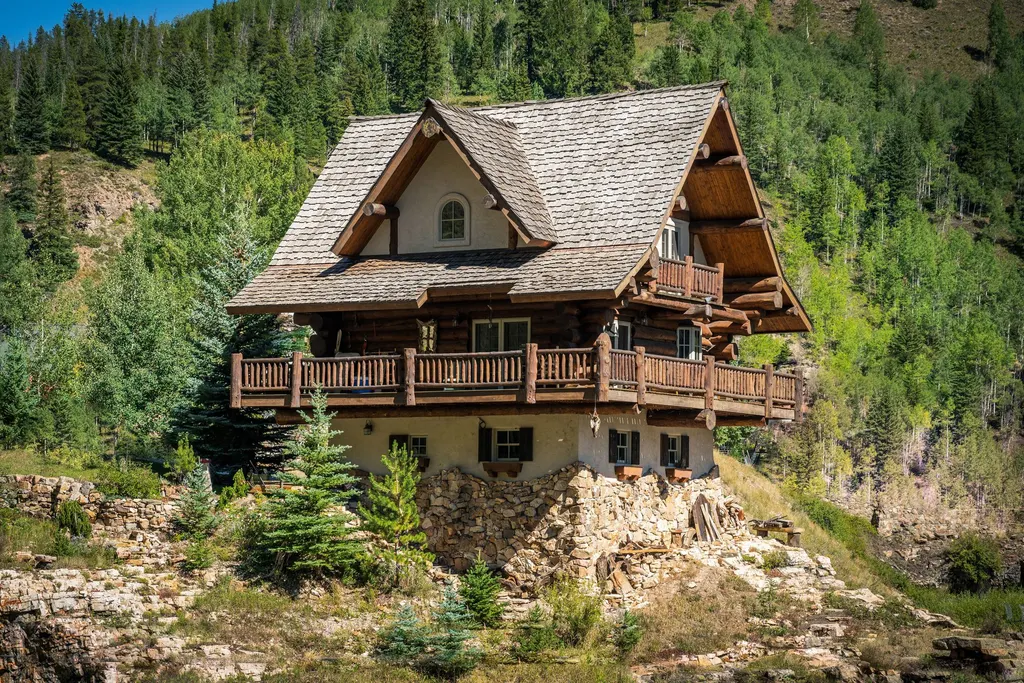 A timber mountain home with wraparound balconies set on a forested hillside in the Colorado high country.