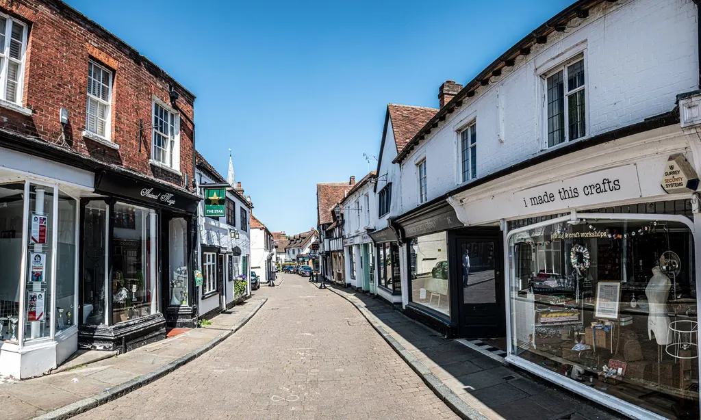 A historic shopping street lined with independent storefronts and boutiques under a clear sky.